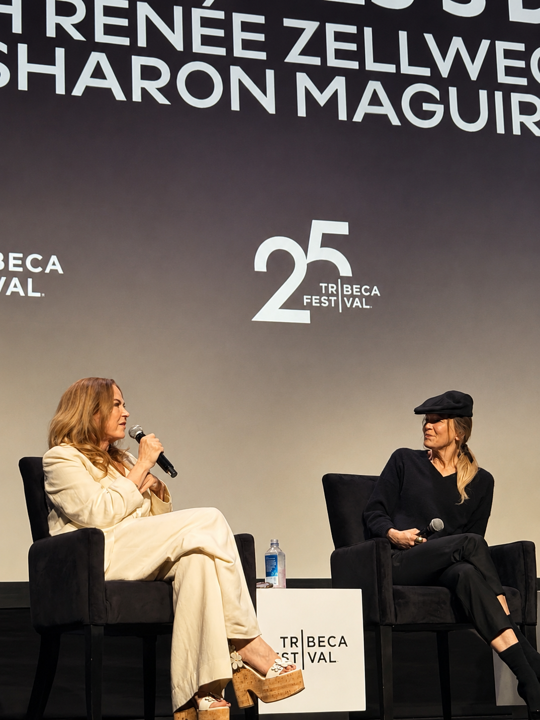 Sharon Maguire speaking while Renée Zellweger listens beside her on stage at the 2026 Tribeca Festival