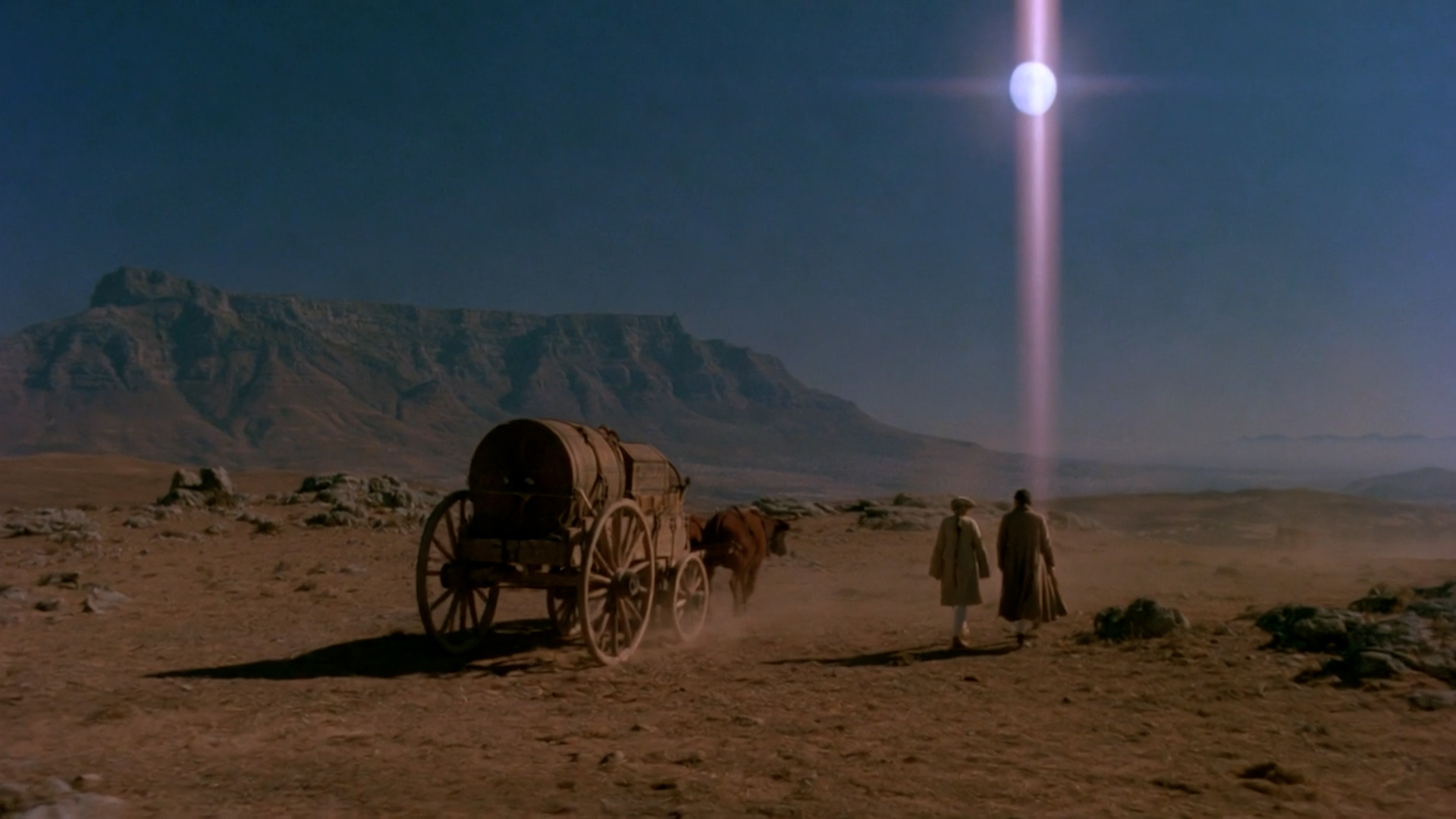 Travelers and a horse-drawn wagon cross a desert landscape in TRANSIT.